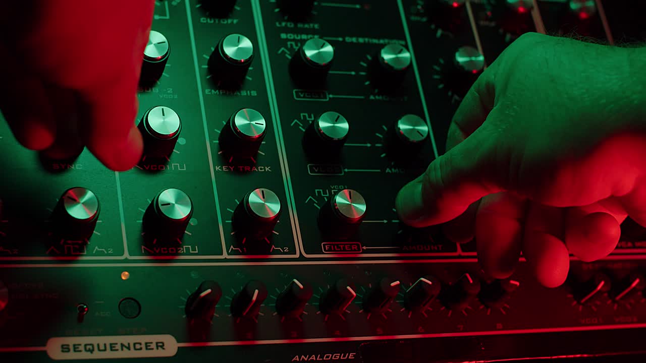 빈티지 신스, 짙은 빨강 및 녹색 분위기에서 손잡이를 돌리는 남자의 느린 동작 매크로 샷