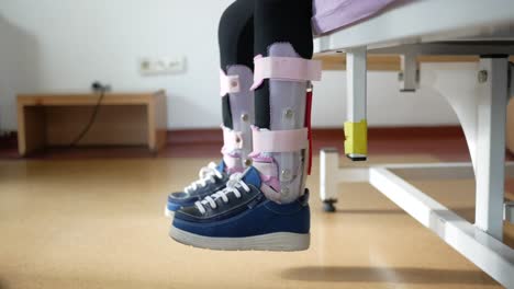 las piernas del niño en aparatos ortopédicos en la cama del hospital
