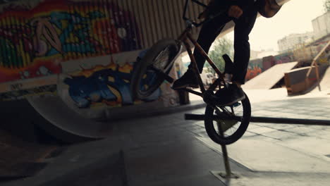 young male hipster riding on bmx bike at urban space. action time in summer