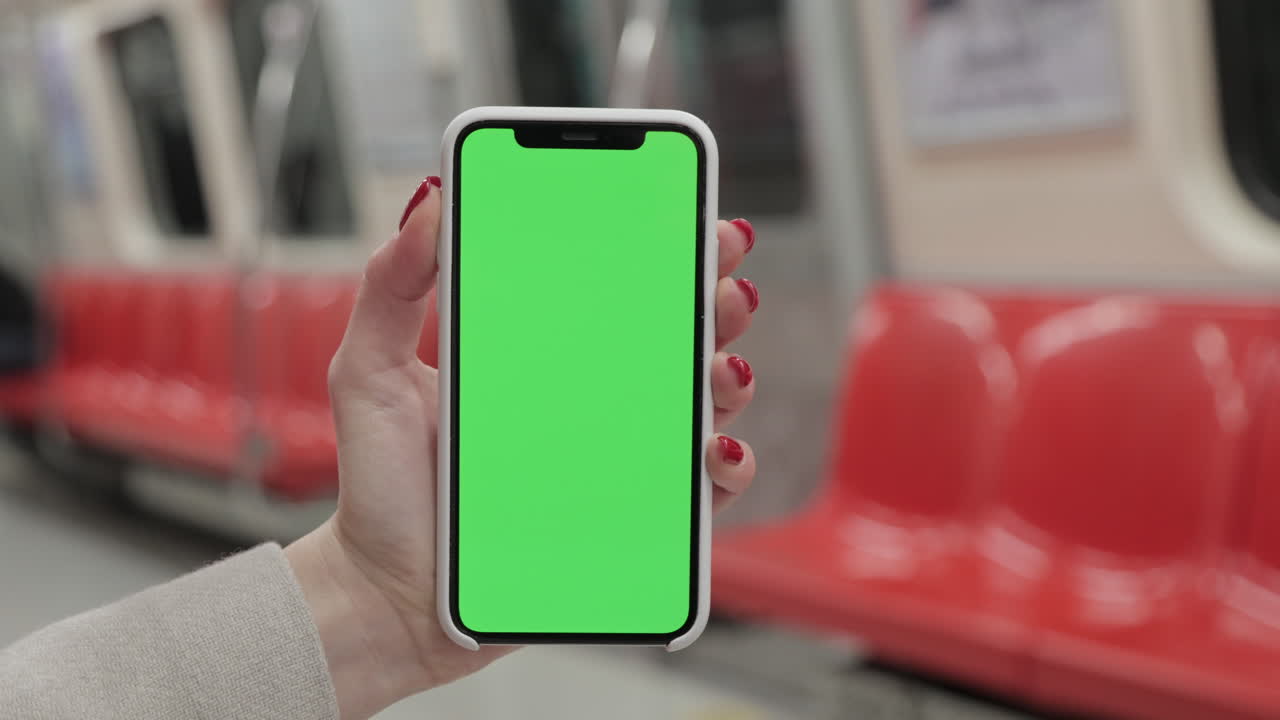 Donna con uno smartphone con schermo verde in metropolitana