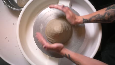woman's hands shaping clay on a pottery wheel