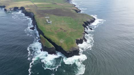 Loop-Head-peninsula-with-waves-crashing-against-cliffs,-lush-greenery-atop