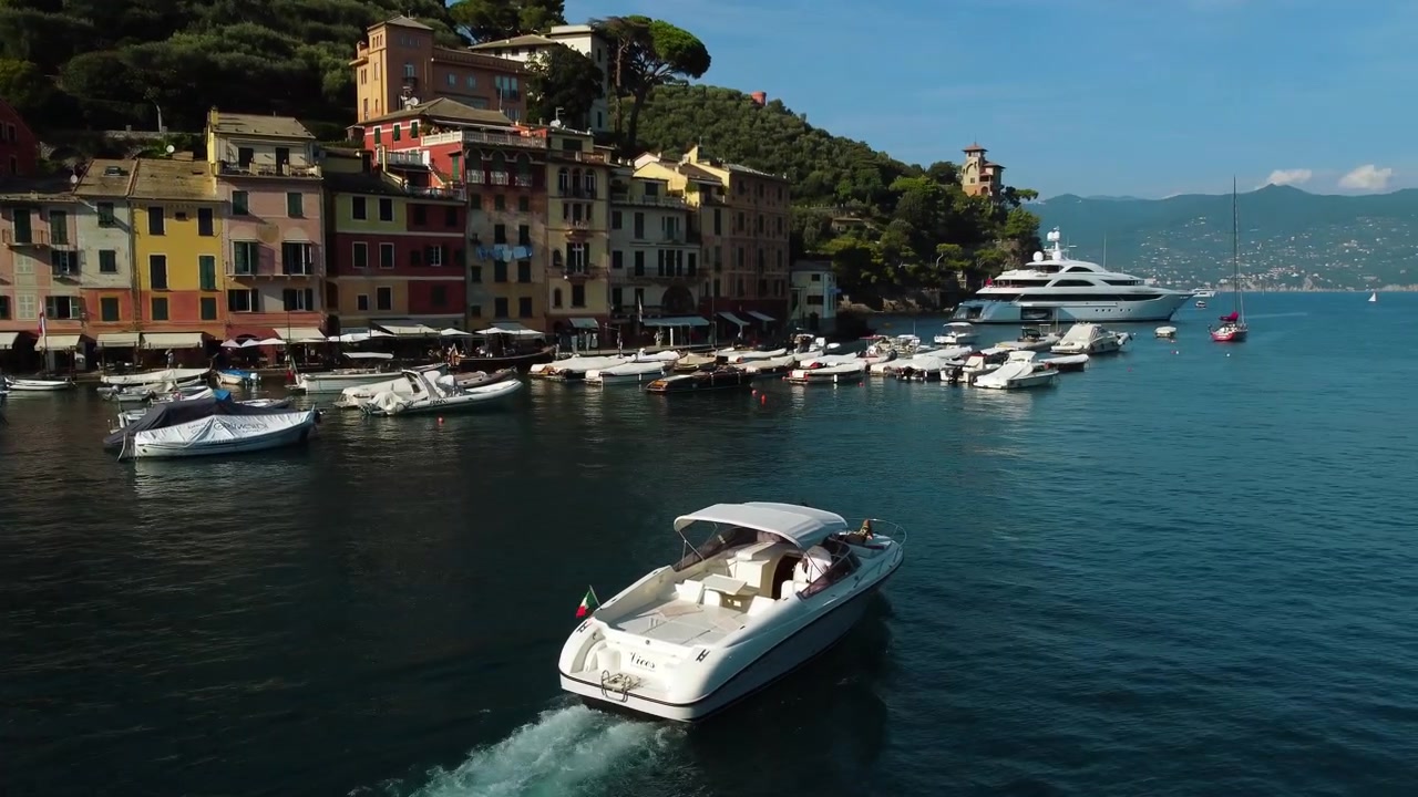 Panoramica aerea che segue una barca nel porto turistico di Portofino, all'ora d'oro in Italia.