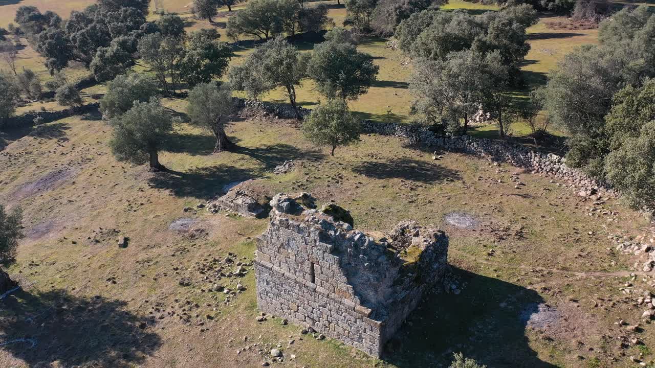 vuelo orbital de drones a una ermita medieval en ruinas del siglo xi como un punto central rodeado de pastos, robles y olivos junto a una carretera rural en el valle de tietar, ávila, españa.