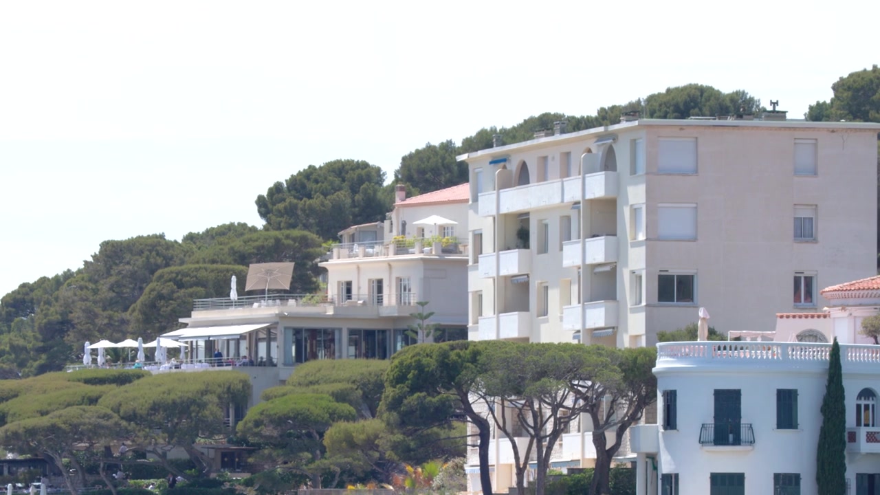 Ripresa panoramica di edifici residenziali mediterranei e pini lungo la costa a Cassis, Francia