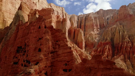 drone explores unique red-orange cave-like structure in dry mountains of dhakmar village, upper mustang, nepal. alluring video showcases detailed landscape and artistic formations in annapurna area