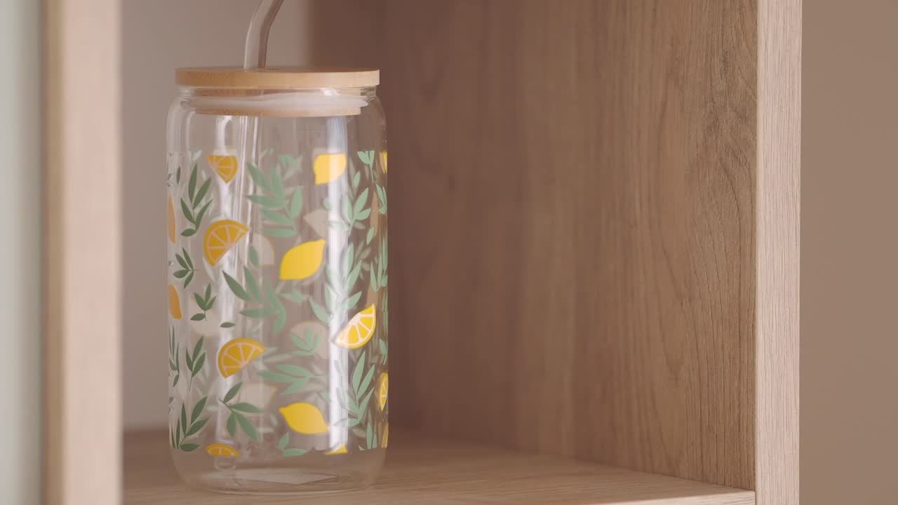 Glass Water Bottle with Lemon Design on Wooden Shelf