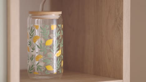 glass water bottle with lemon design on wooden shelf