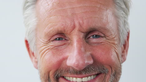 Close-Up-Of-Studio-Shot-Of-Senior-Man-Against-White-Background-Laughing-At-Camera