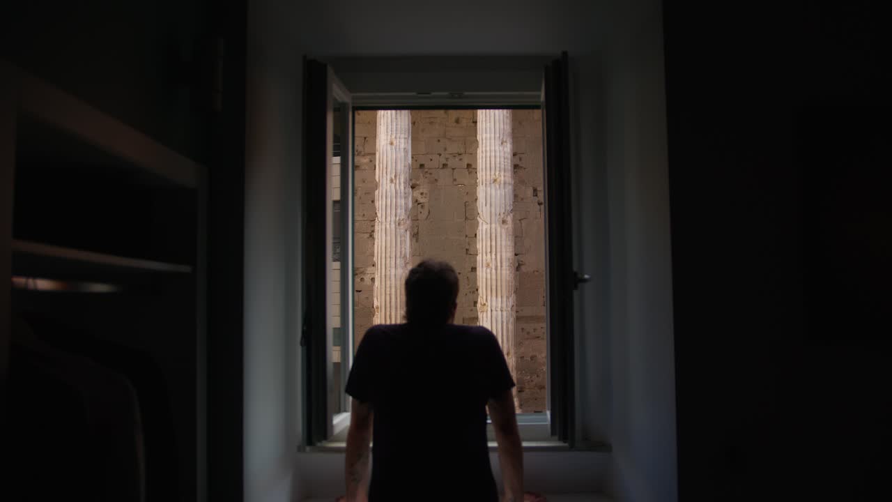 A person gazing out a window at ancient Roman architecture near the Pantheon