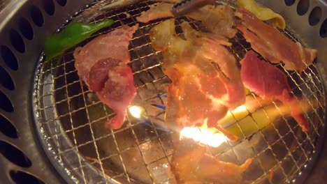 tongs flipping grilled meat on yakiniku all you can eat japanese barbecue