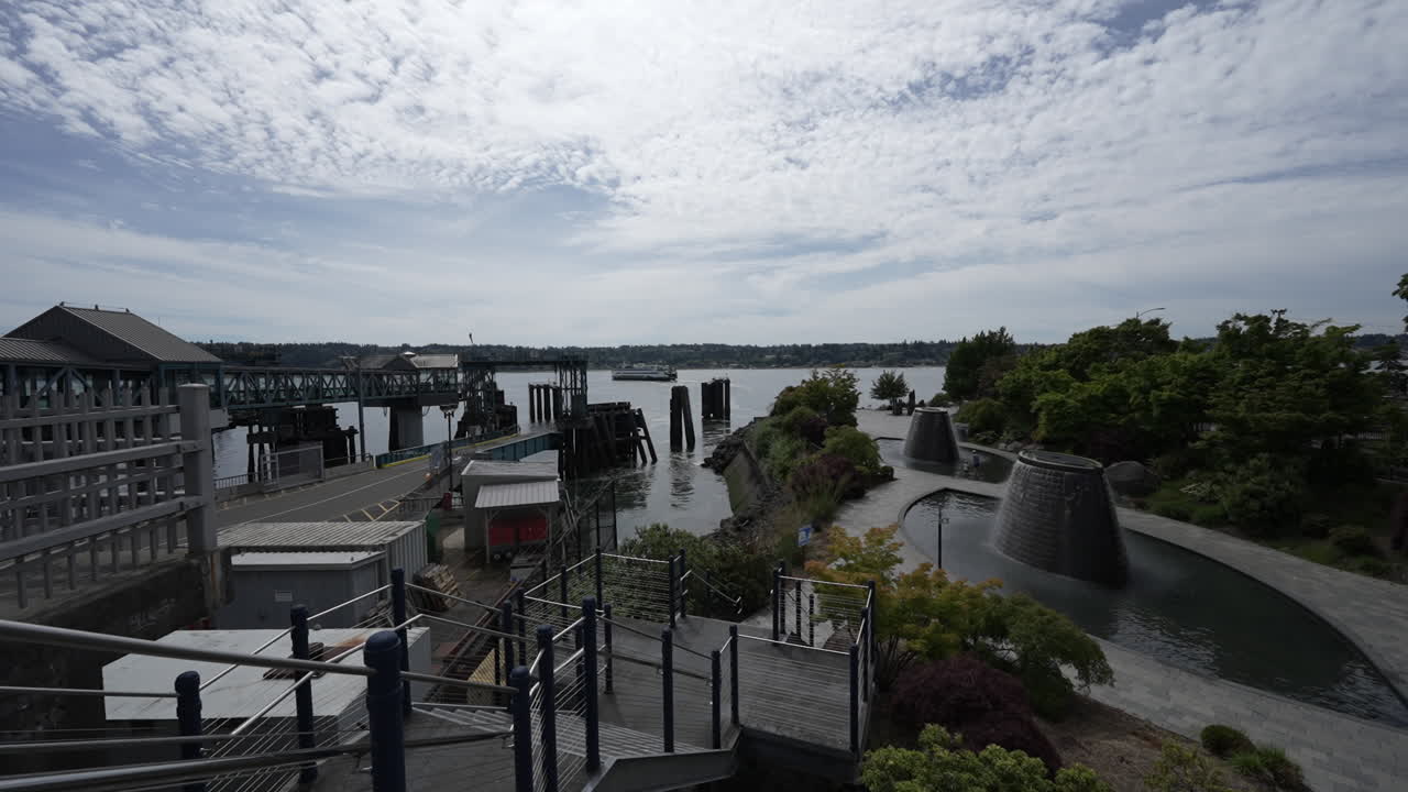 A ferry leaving the Bainbridge Island Ferry Terminal, with the dock and surrounding landscape visible under a partly cloudy sky. Timelapse Video.