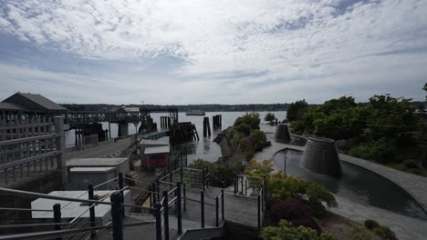 a ferry leaving the bainbridge island ferry terminal, with the dock and surrounding landscape visible under a partly cloudy sky. timelapse video.