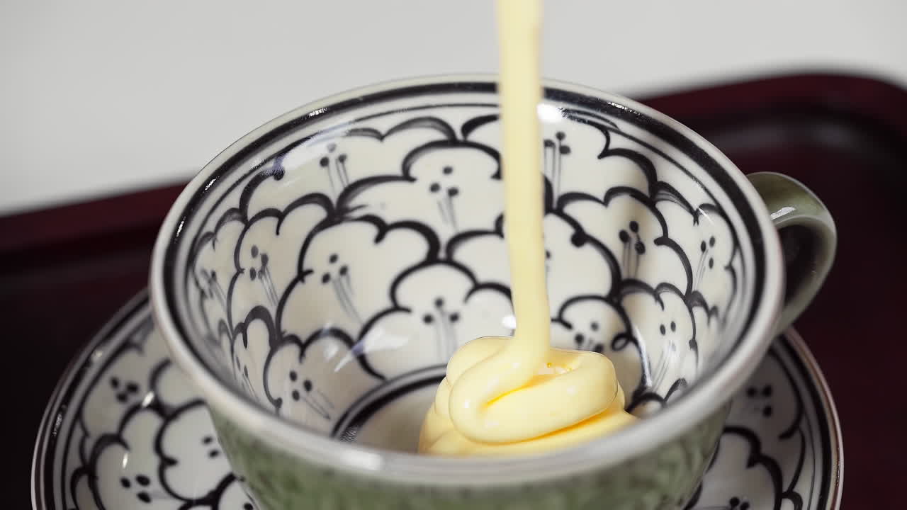 Pouring whipped egg york into ceramic cup