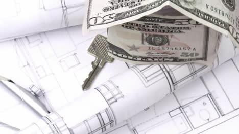 close up of plans, dollar house and keys turning