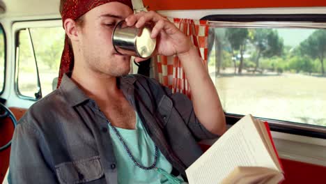 Man-reading-novel-while-having-coffee-in-camper-van-4k