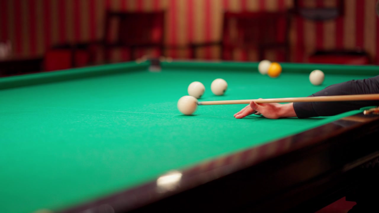 Close-up of a Hand Playing Billiards on a Green Pool Table