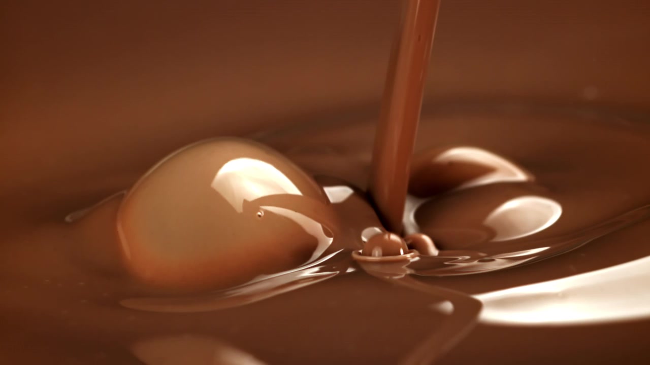 Primo piano al rallentatore di colata di cioccolato fuso liquido.