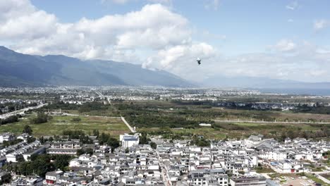 Cartoon-helium-balloon-rising-above-Chinese-city,-rising-aerial-view