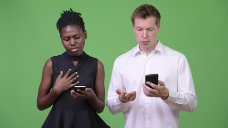 two young multi-ethnic business couple using phone together