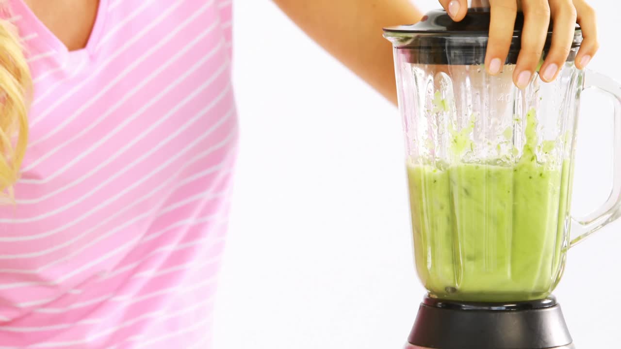 Donna che prepara un frullato di verdure su sfondo bianco