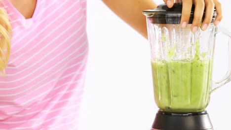 woman preparing vegetable smoothie against white background