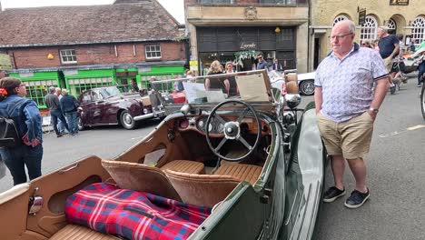 people admire vintage cars on a busy street