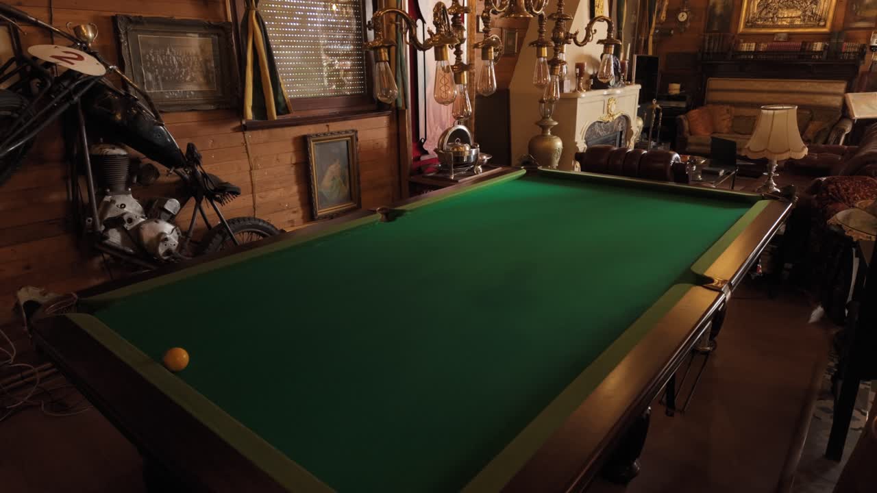 green billiard table surrounded by vintage decor in warm nostalgic room