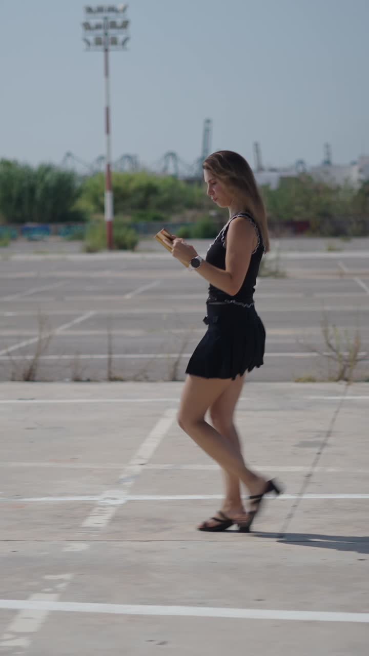 Woman walking and reading in a parking lot