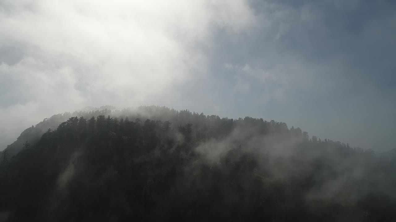 천천히 움직이는 드론은 산 꼭대기에 굴러가는 안개를 습니다.