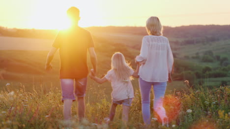 a friendly family has fun weekend walking through the fields at sunset