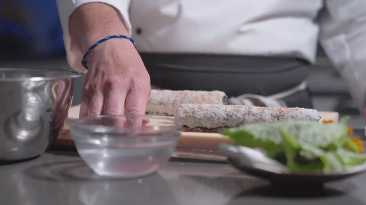 A sliding shot captures sushi rolls being sliced into individual pieces, highlighting the precision and craftsmanship. Ideal for culinary, sushi, and food preparation content.