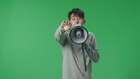 asian man speaking on megaphone in the green screen studio
