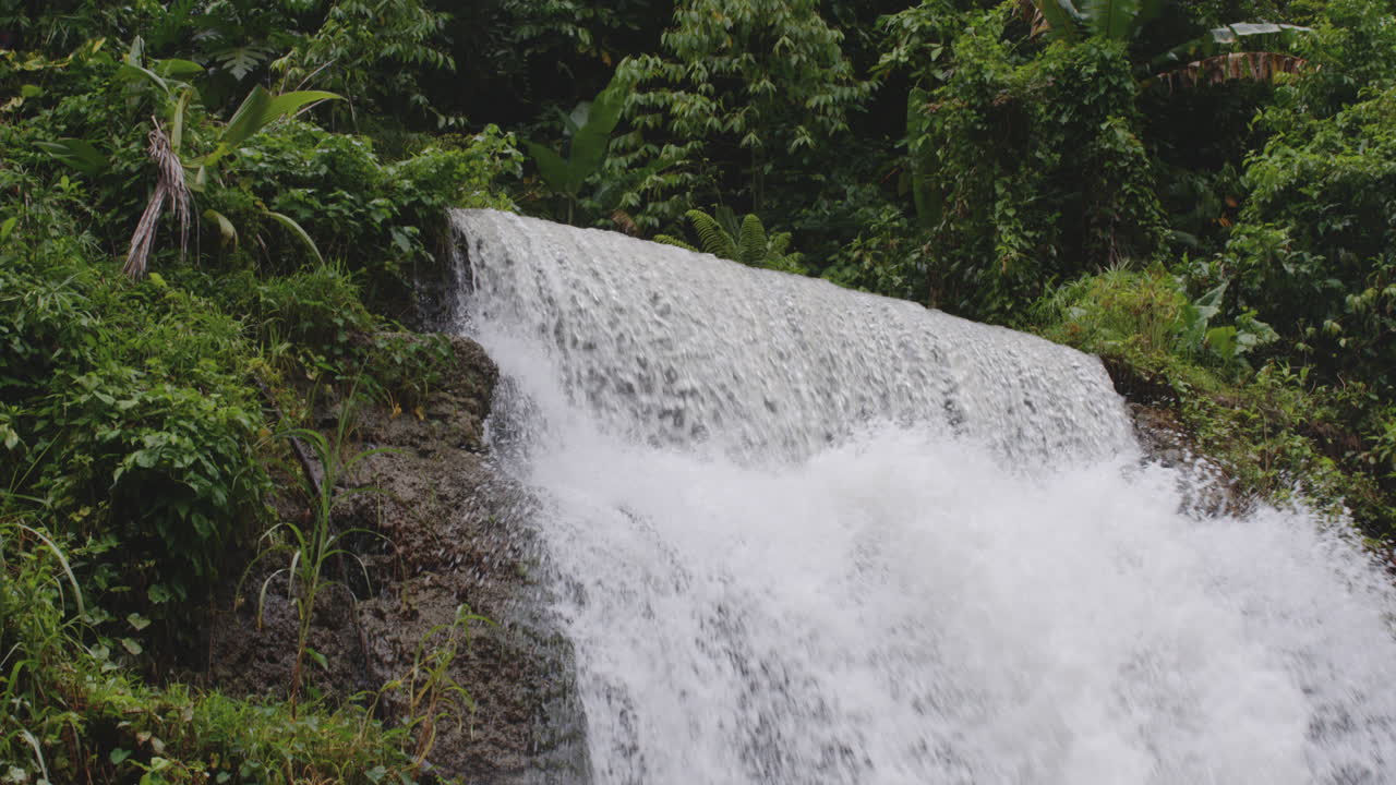 fuerte corriente que fluye sobre colinas rocosas cubiertas de musgo en la primera cascada de la planta en tanamá, arecibo, puerto rico