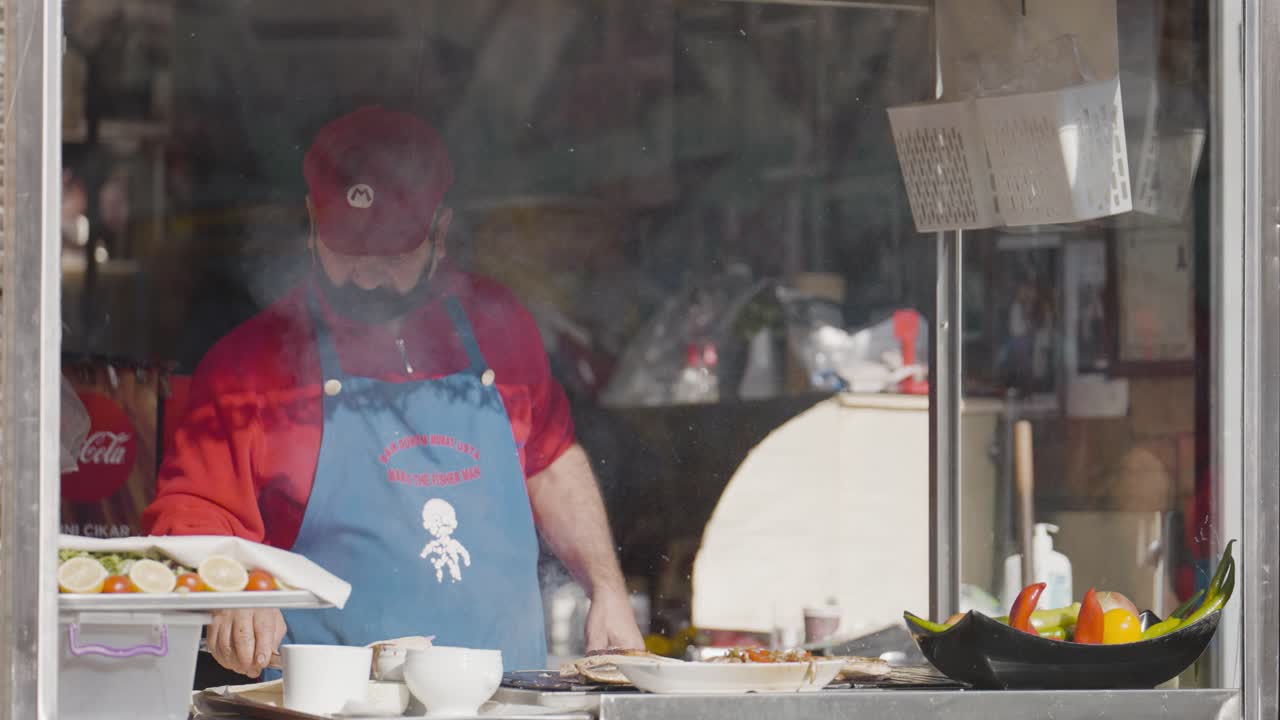 vendedor callejero de comida preparando pescado a la parrilla