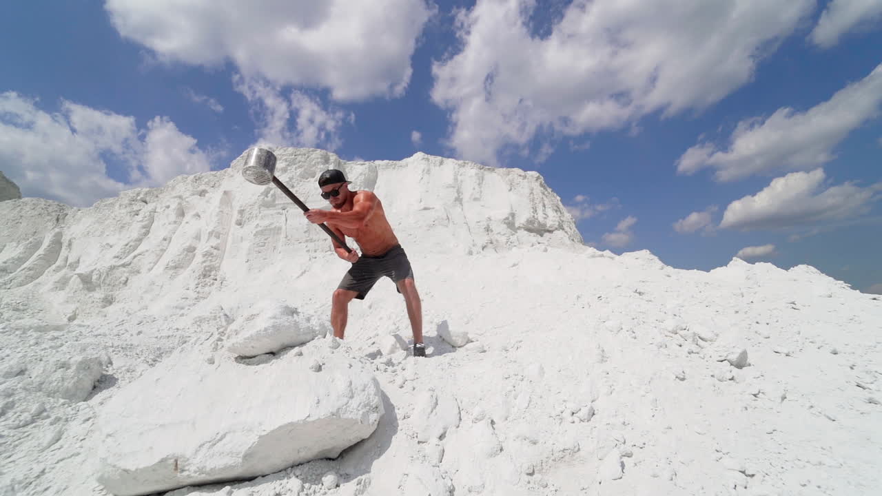 Man doing hammer strike during exercise outside. Sport fitness man hitting stone with hammer during crossfit training