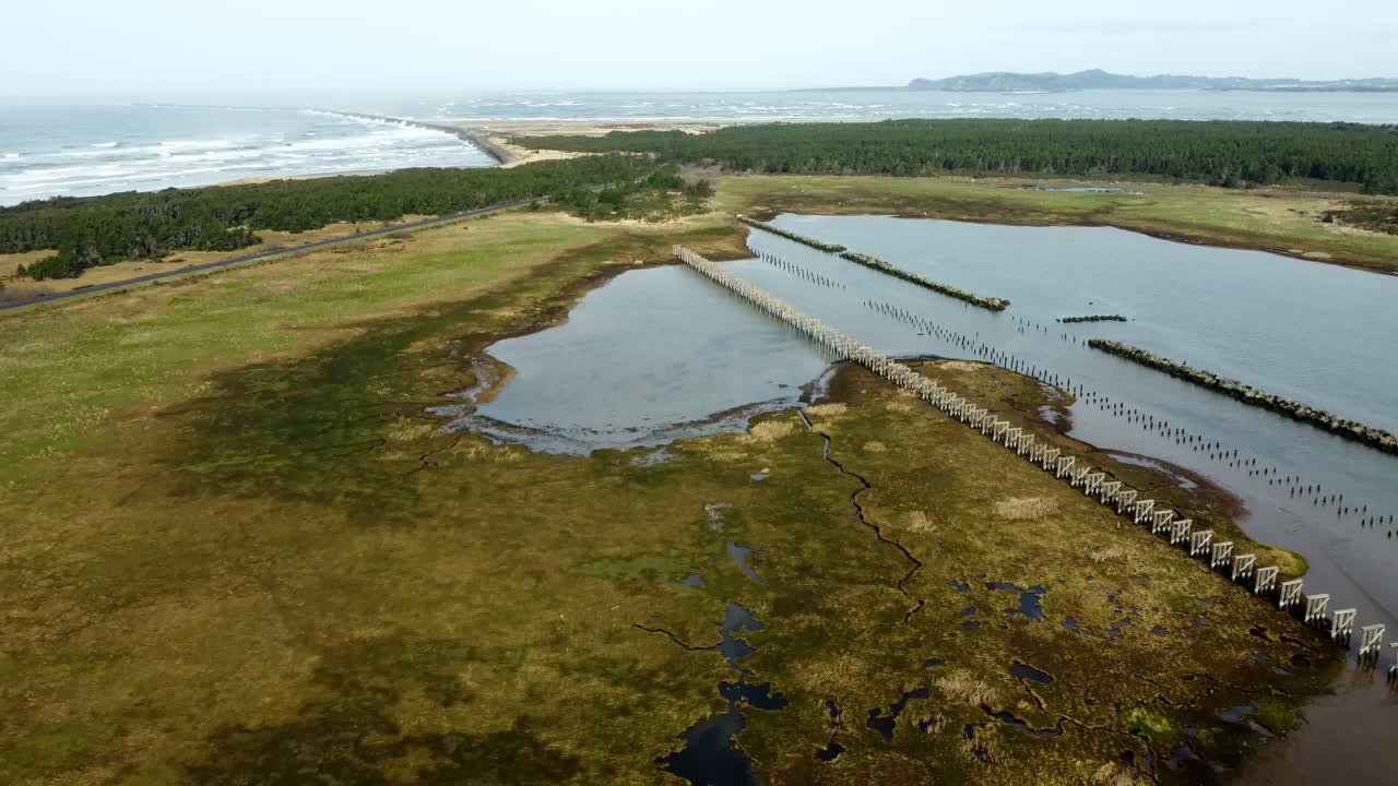 US, Oregon, Astoria, Fort Stevens, 2025-03-21 - Drone view of the Columbia River at the Pacific Ocean. This old railroad trestle from the early 1900's was used to build the rock jetty.