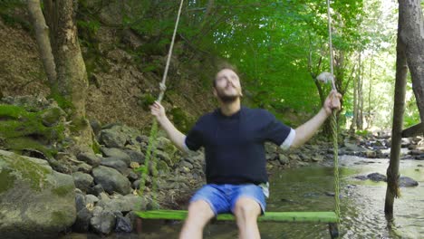 the young man swinging on the swing in the creek.