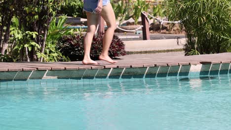 person walking by pool then jumping into water