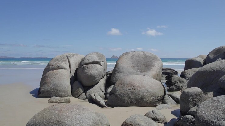 Massicci massi sulla spiaggia isolata di Whisky Bay a Wilsons Promontory con vista su Norman Island in lontananza. Ripresa aerea bassa