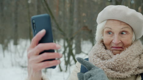 senior woman taking a selfie in a snowy forest