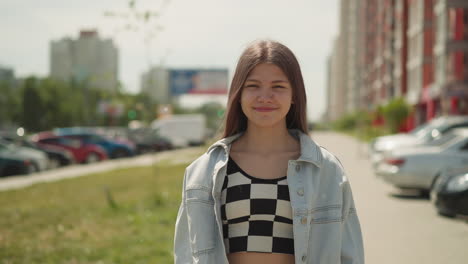 positive teenage girl smiles looking at camera on summer day