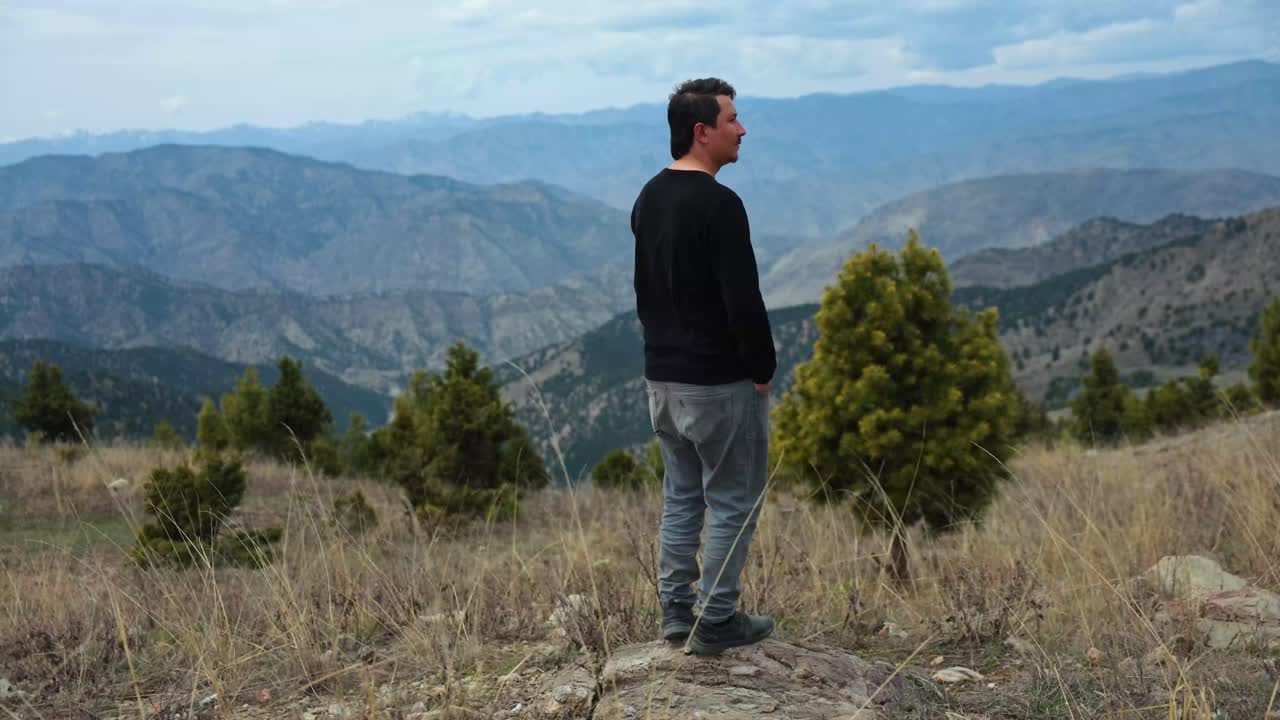 Uomo in piedi su una montagna che domina un vasto paesaggio