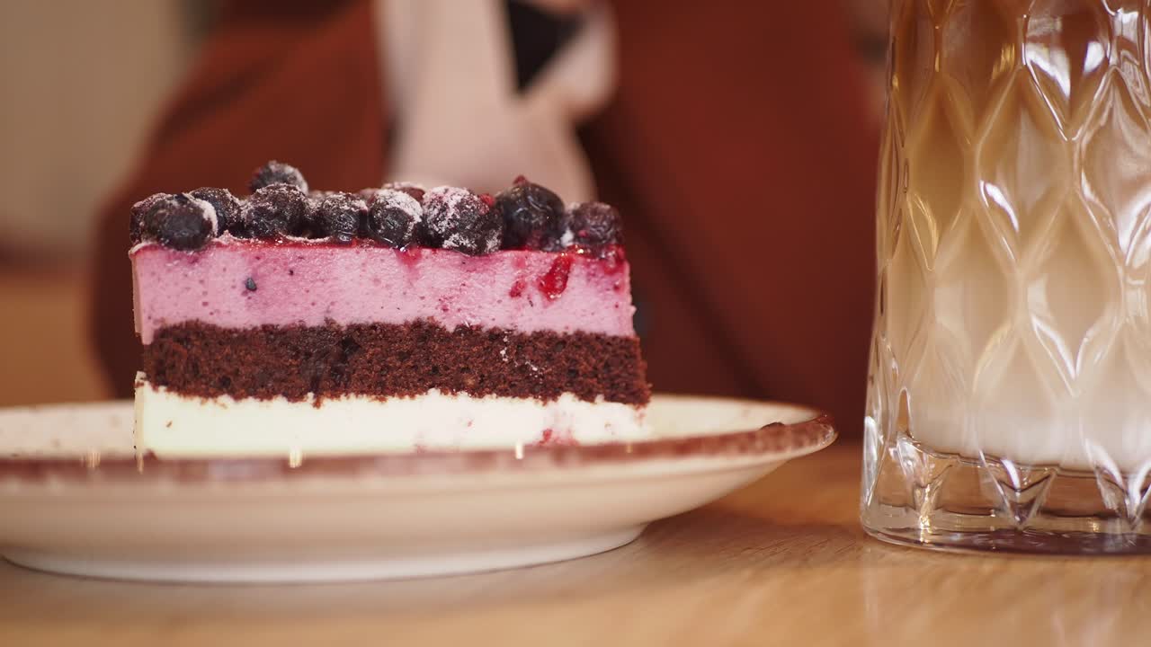 얼음 커피 한 잔과 함께 제공 된 휘프 크림과 초콜릿 층으로 블루베리 케이크 한 조각의 클로즈업