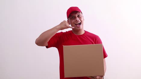 young asian courier man holding cardboard while making phone hand gesture