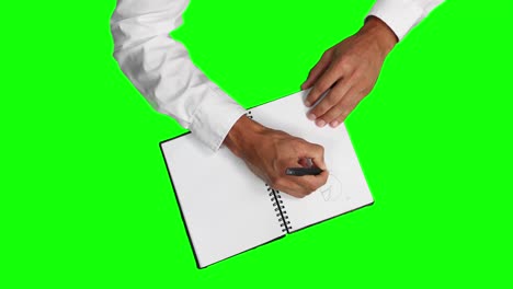 Overhead-view-of-a-caucasian-man-drawing-graphs-in-a-notebook-with-green-screen