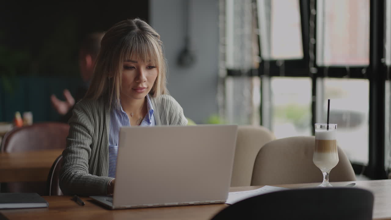 Young Asian attractive female office worker sitting at the laptop computer at the desk working and thinking.