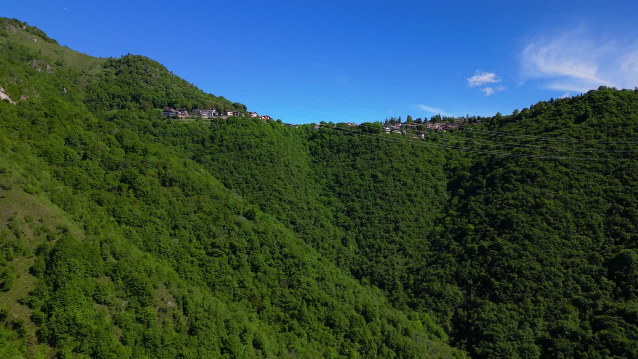 Expansive aerial view of Selvino village spread across the green mountains with distant peaks and clear skies. Shot at Selvino, Italy (Selvino, Italia)