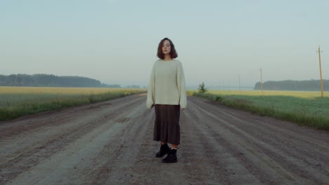 해가 뜨는 시골 도로에 서 있는 소녀