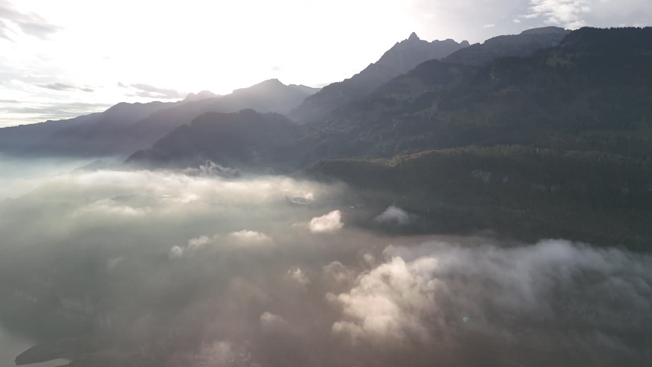 Early morning fog aerial Swiss alpine mountain valley, nature travel drone